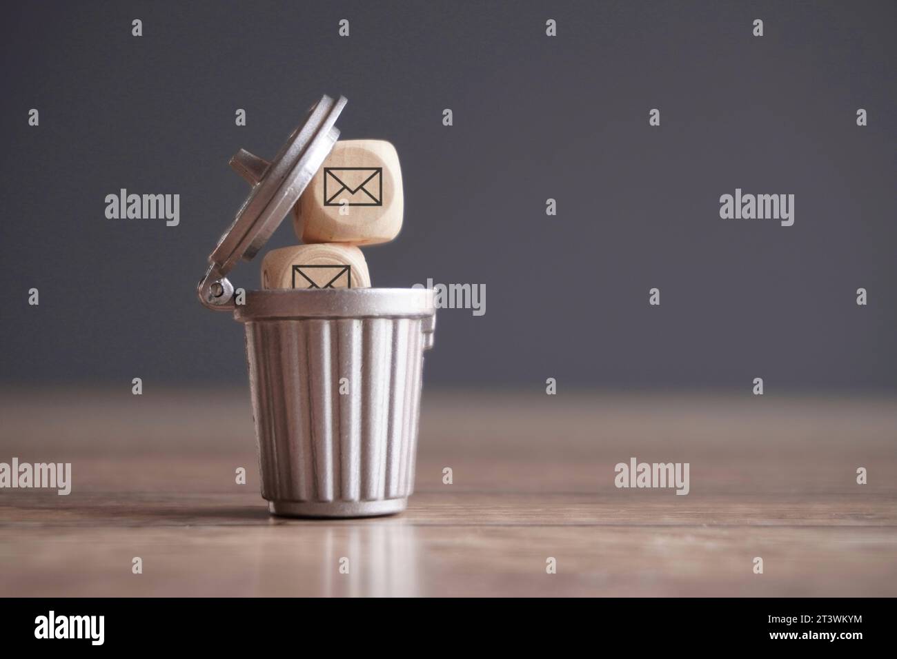 Closeup image of wooden cube with mail icon inside trash can. Junk mail and spam mail concept. Stock Photo