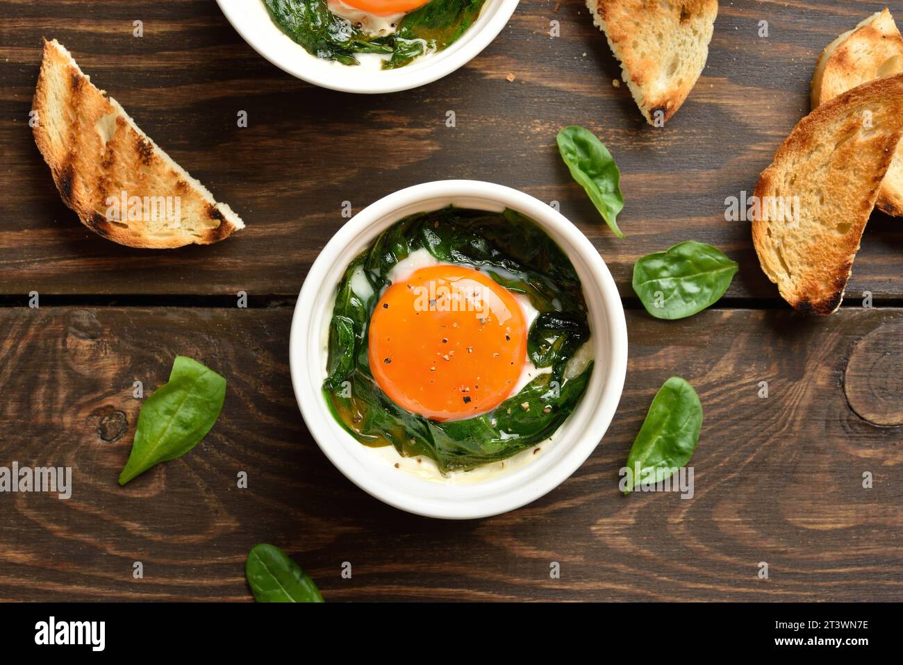 Baked eggs(Eggs en cocotte ) in ramekins and toasted bread over wooden