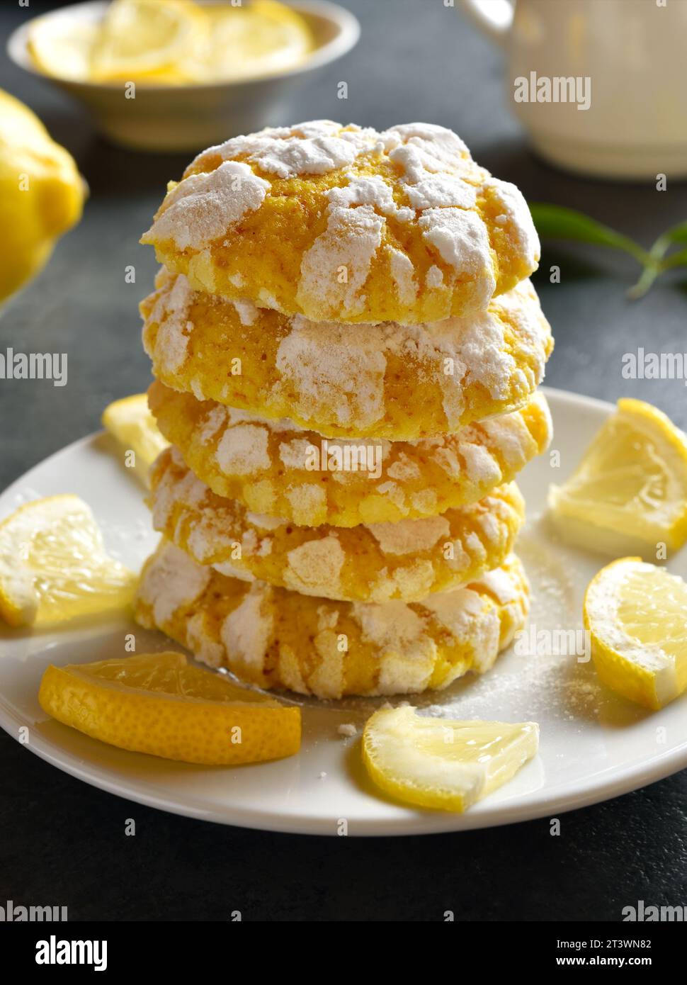 Stack of homemade lemon crinkle cookies on plate over dark stone background. Close up view Stock Photo