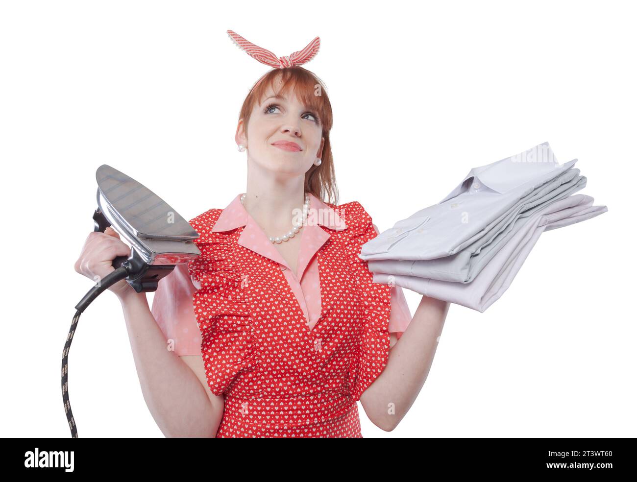 Vintage style efficient housewife holding an iron and a pile of clean ironed shirts Stock Photo
