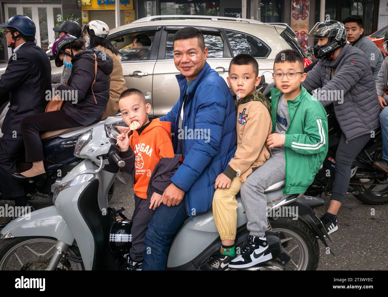 A Vietnamese man and three young boys ride on a motorcycle without helmets at tet, or lunar new year, in Hanoi, Vietnam. Stock Photo