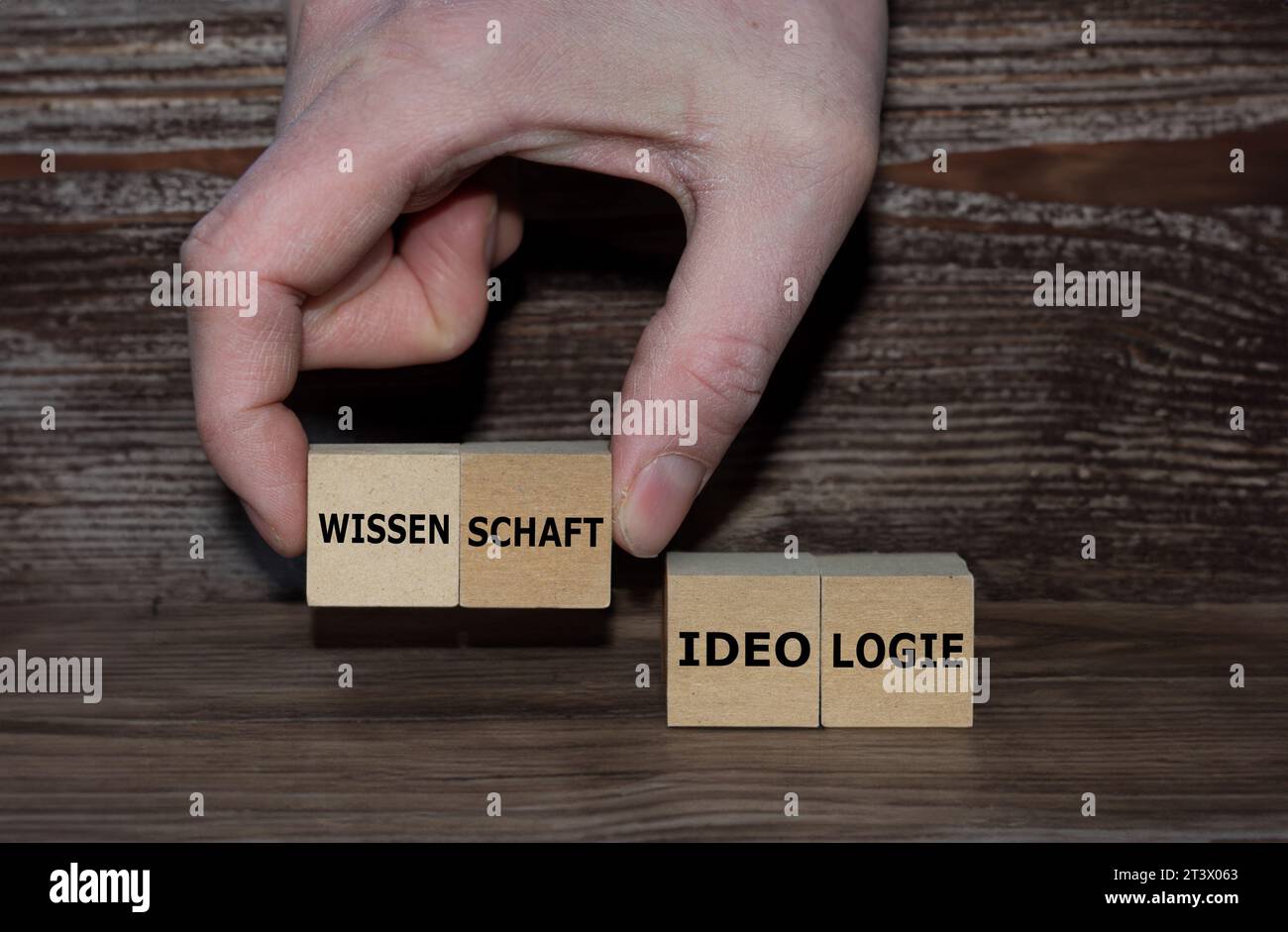 Hand picks cubes with the German word 'Wissenschaft' (science) instead of 'Ideologie' (ideology). Stock Photo