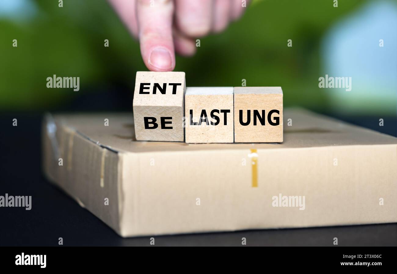 Hand turns cube and changes the German expression 'belastung' (strain) to 'entlastung' (relief). Symbol for the financial relief package in Germany. Stock Photo