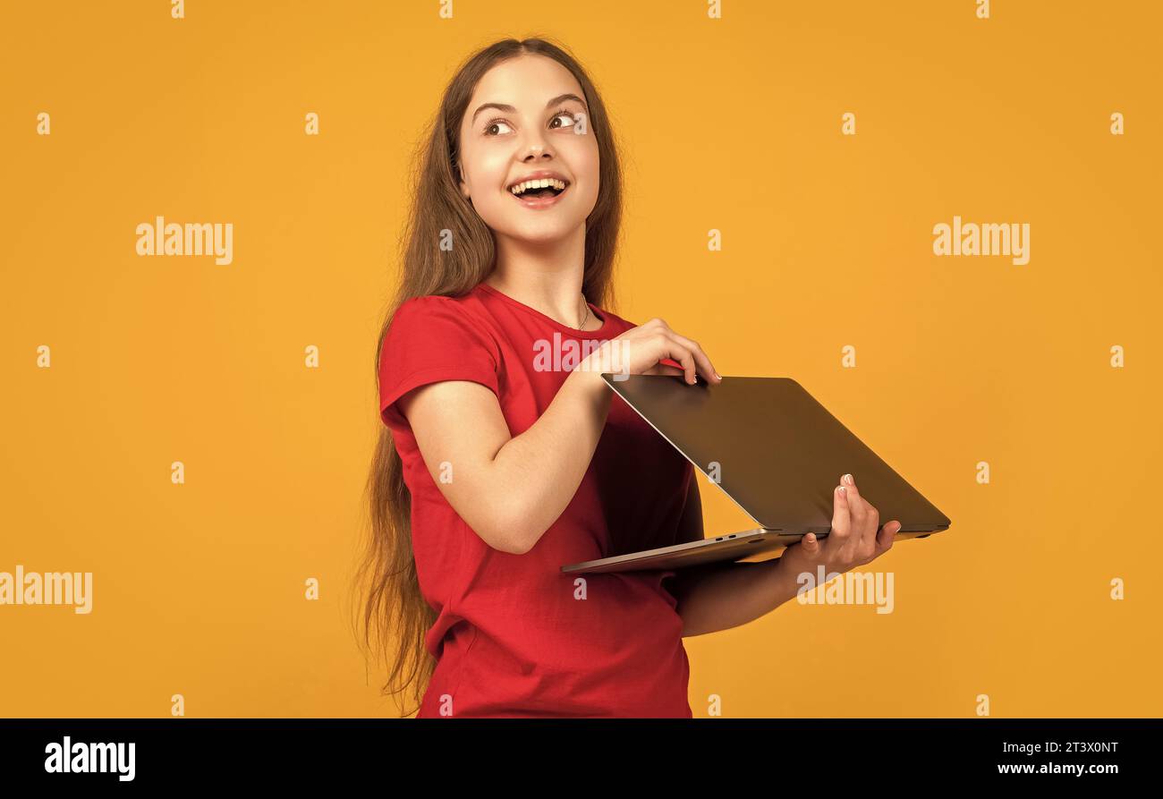 amazed child with laptop on yellow background Stock Photo - Alamy
