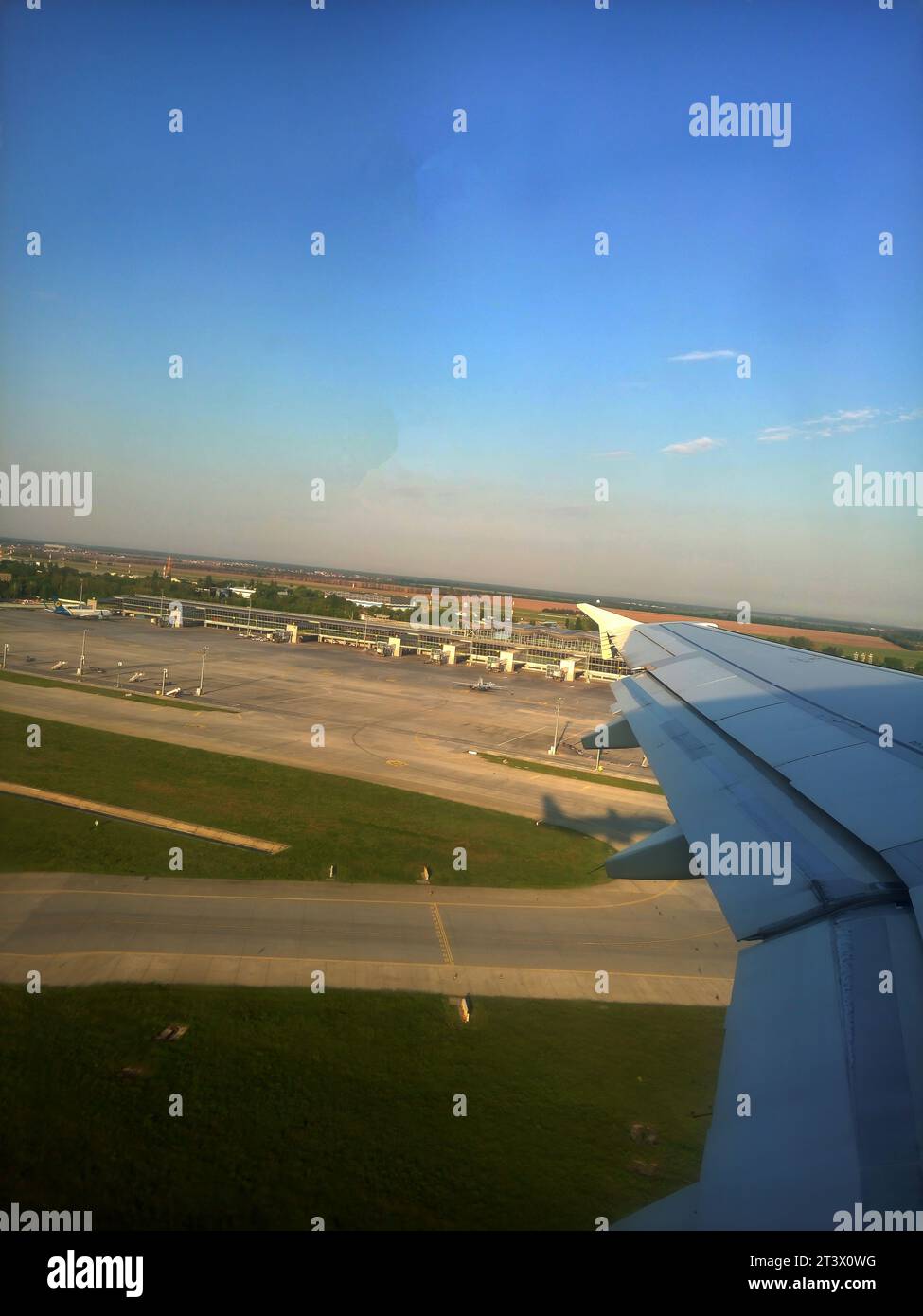 Plane flies over Boryspil airport, Ukraine. Plane metal wing shining in the sunrays Stock Photo