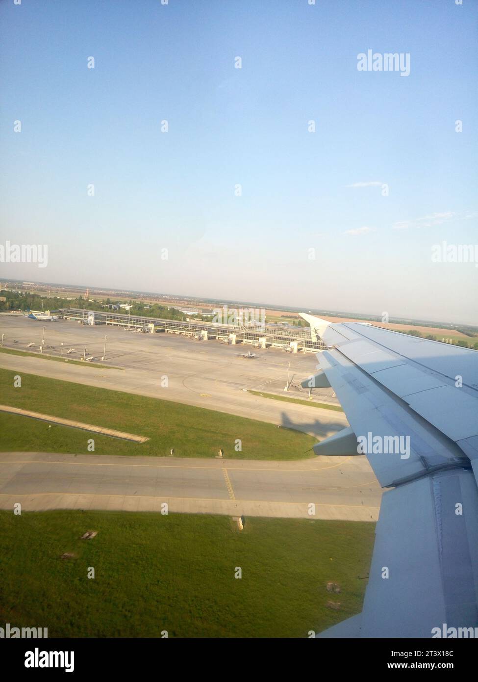 Plane flies over Boryspil airport, Ukraine. Plane metal wing shining in the sunrays Stock Photo