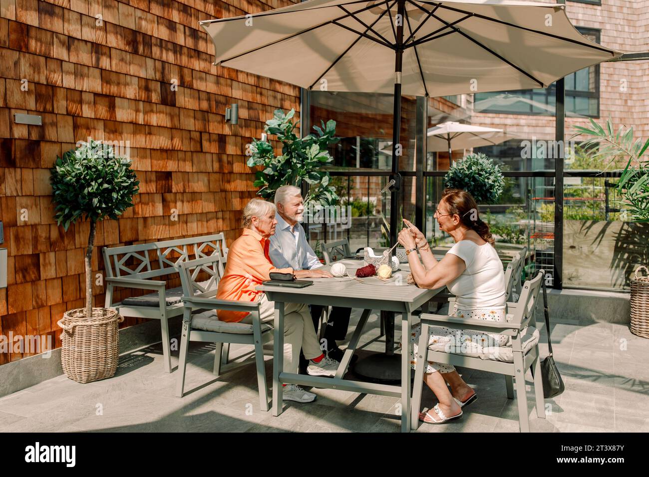 Senior man and women talking while sitting at dining table on sunny day Stock Photo
