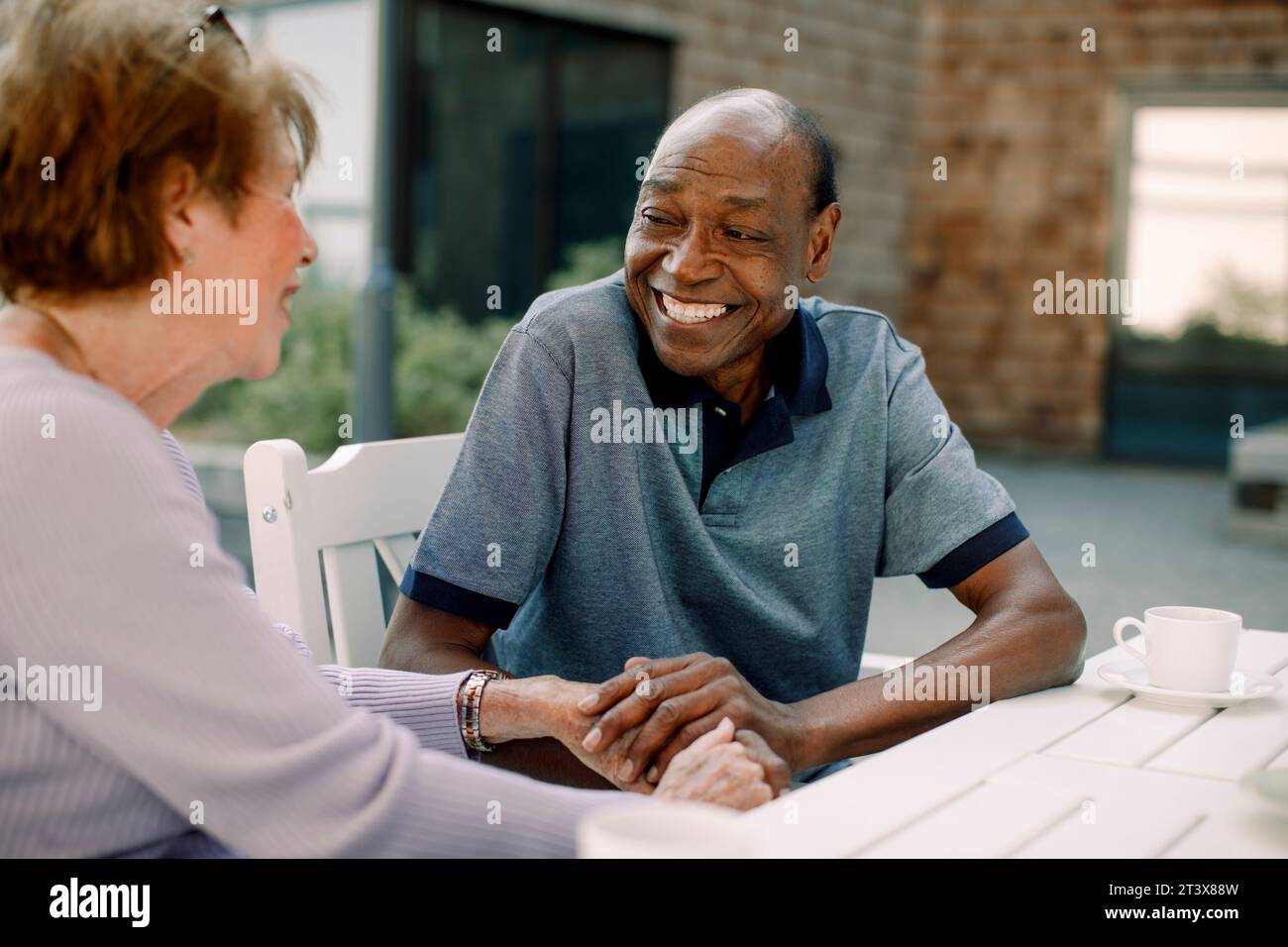 Happy senior man talking to woman while sitting at dining table Stock Photo