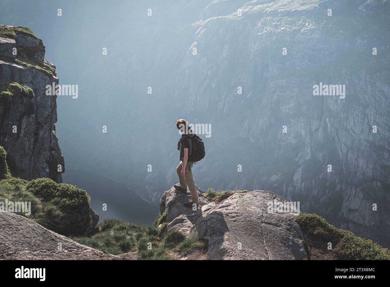 Hiker standing on the edge of a cliff and enjoying the view Stock Photo