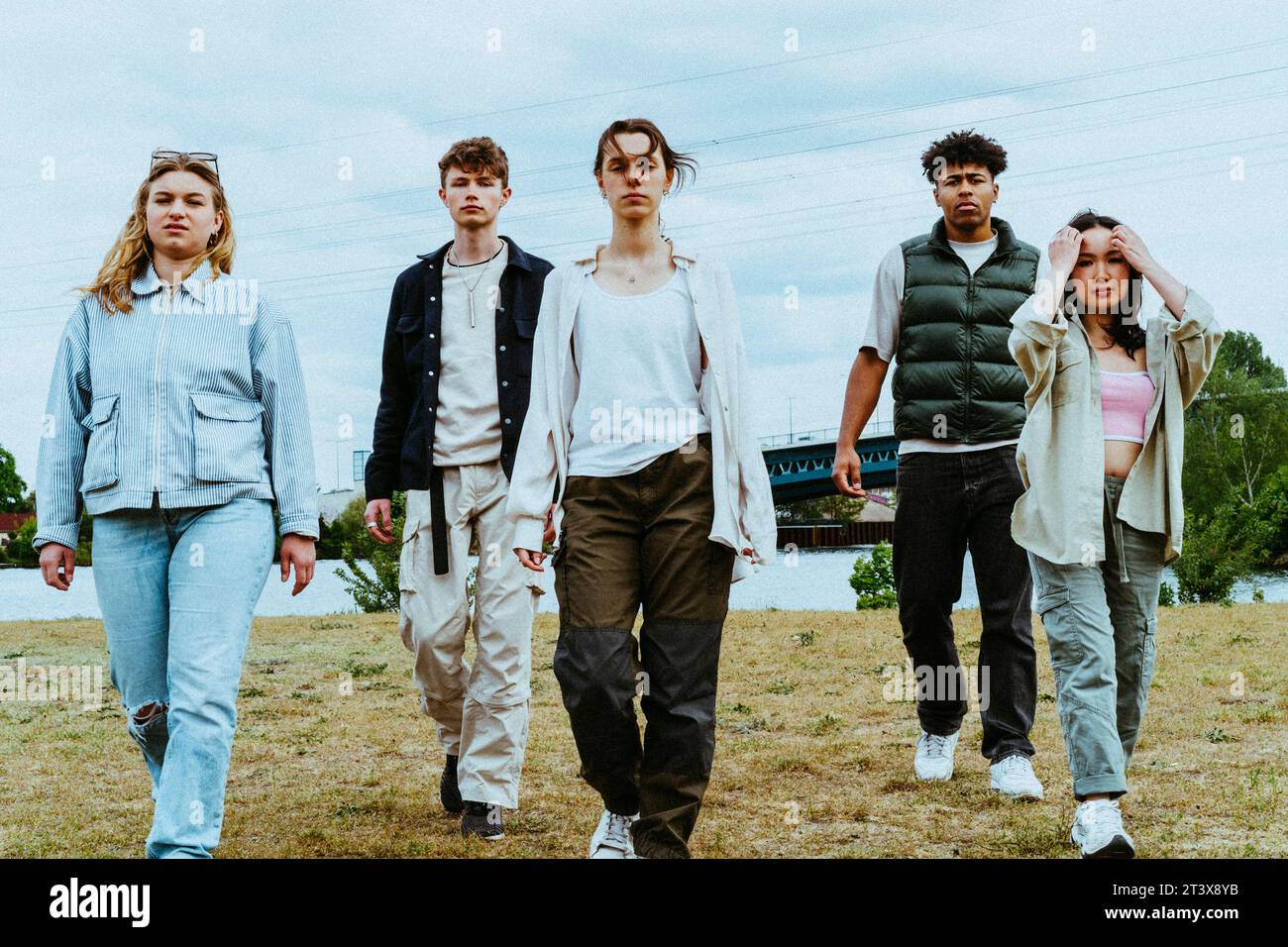 Full length portrait of confident young friends walking against sky Stock Photo