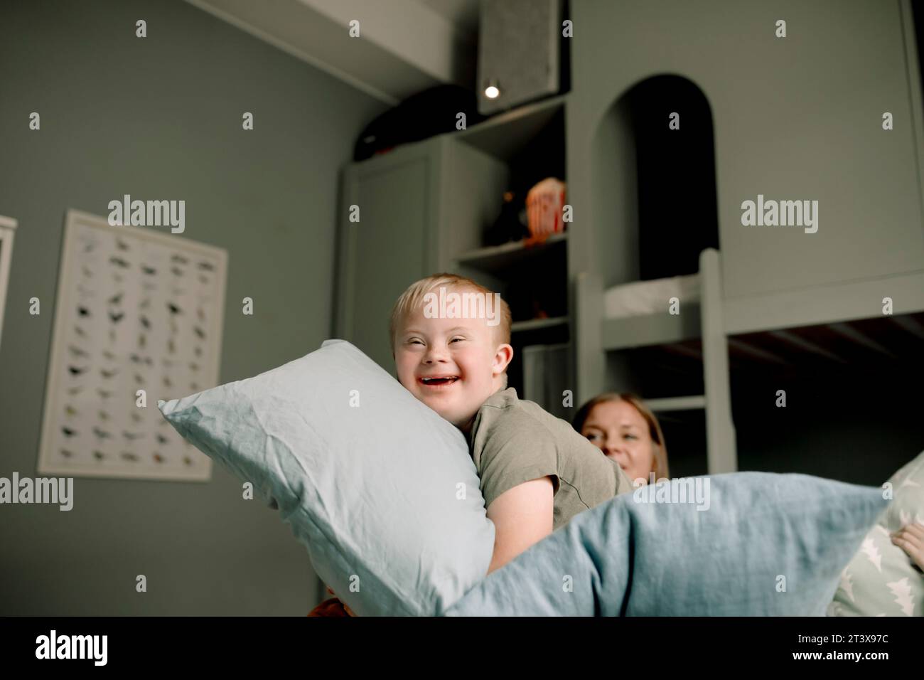Side view of happy boy playing with pillows in bedroom at home Stock Photo