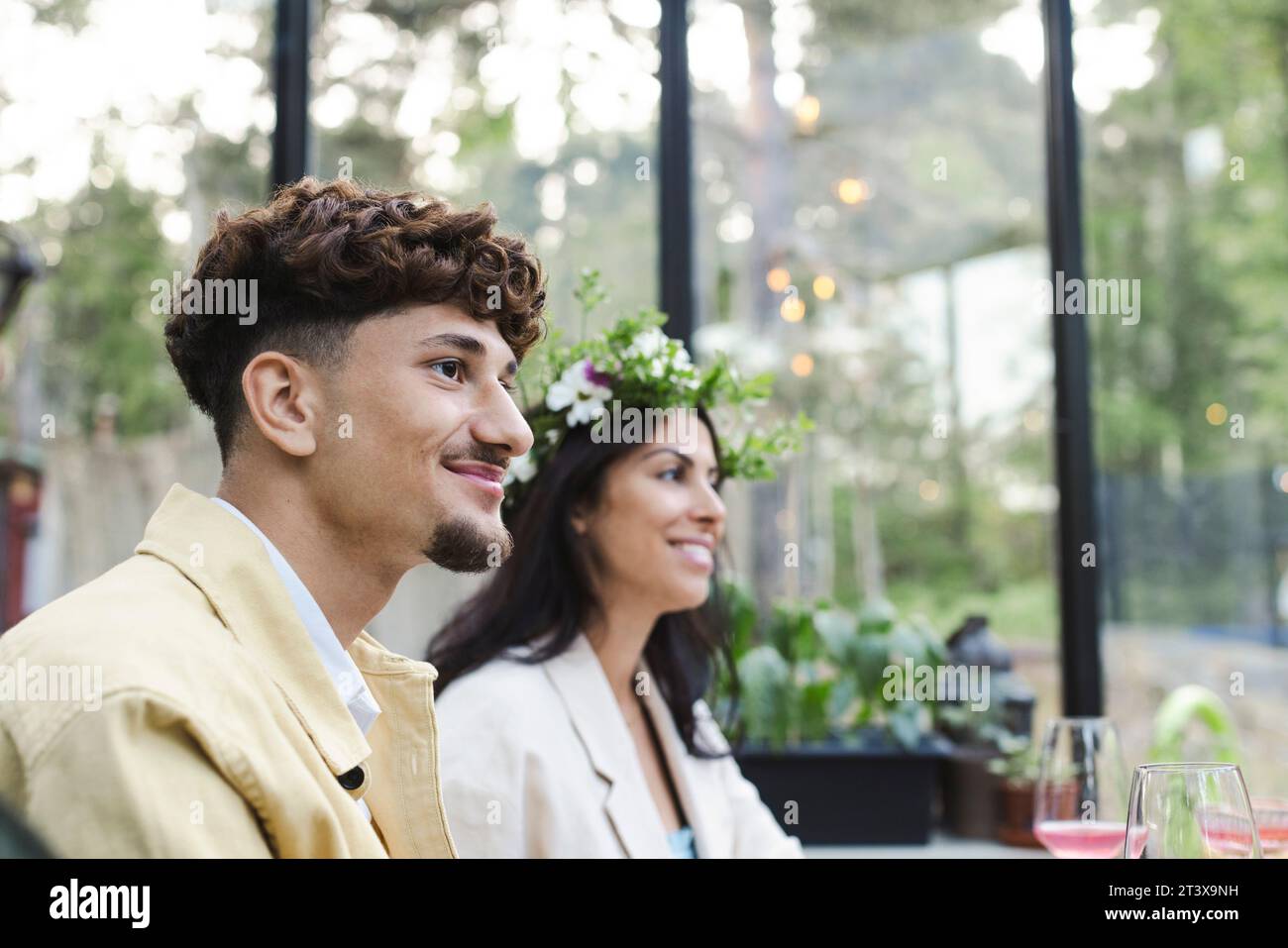 Smiling man sitting by woman wearing tiara at dinner party Stock Photo