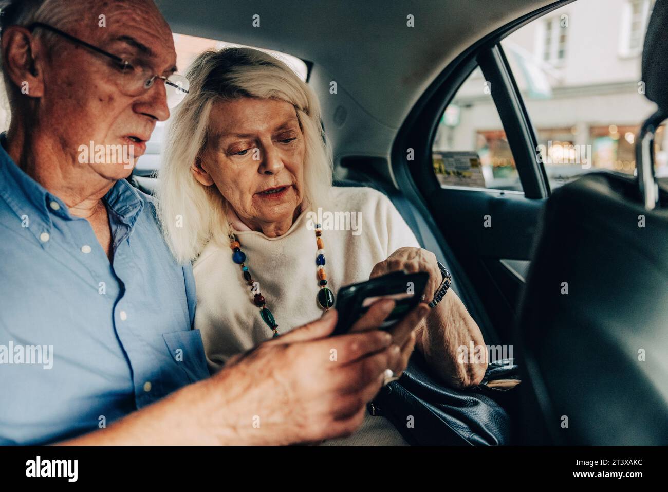 Senior couple using smart phone while sitting in taxi Stock Photo