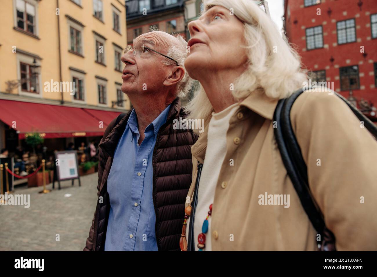 Senior couple looking up while standing together in city Stock Photo