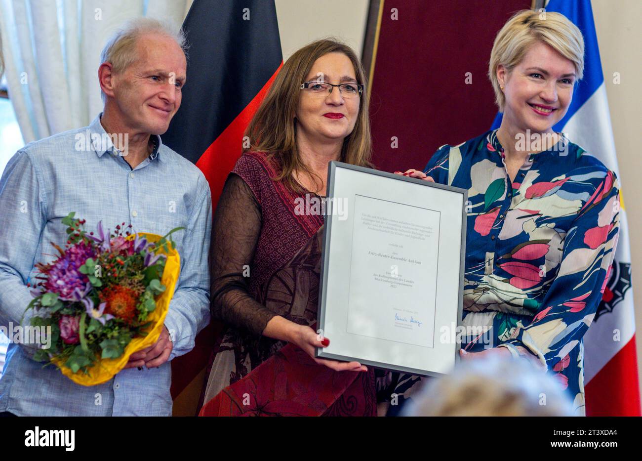 Schwerin, Germany. 27th Oct, 2023. Torsten Wiedemann and Mareike Scheil (M) from the Fritz Reuter Ensemble Anklam receive the Cultural Promotion Award of the State of Mecklenburg-Western Pomerania from Manuela Schwesig (SPD), the Minister President of Mecklenburg-Western Pomerania, at the ceremony in Schwerin Castle. The association is celebrating its 50th anniversary and is dedicated to children and youth work in the field of dance and acrobatics. Credit: Jens Büttner/dpa/Alamy Live News Stock Photo