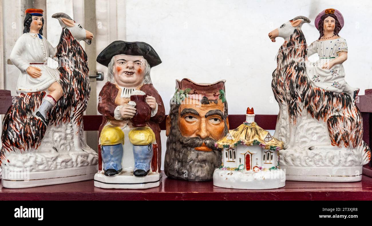 Antique Staffordshire china ornaments for sale at a country antiques fair, including a Toby Jug and a pair of female figures riding on goats (UK) Stock Photo