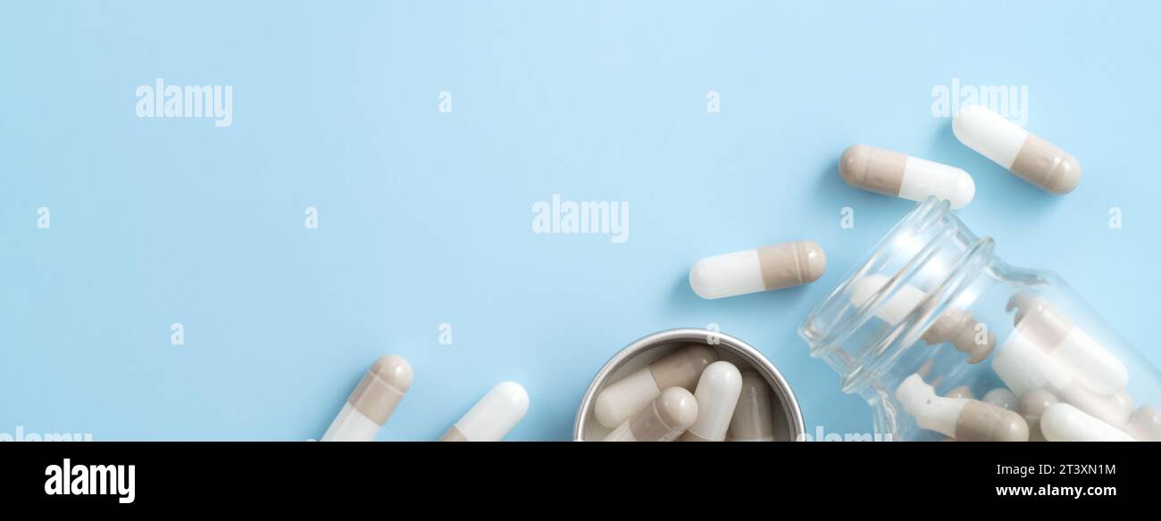 Taking medicine design concept, top view of capsule pills spilled over blue table background. Stock Photo