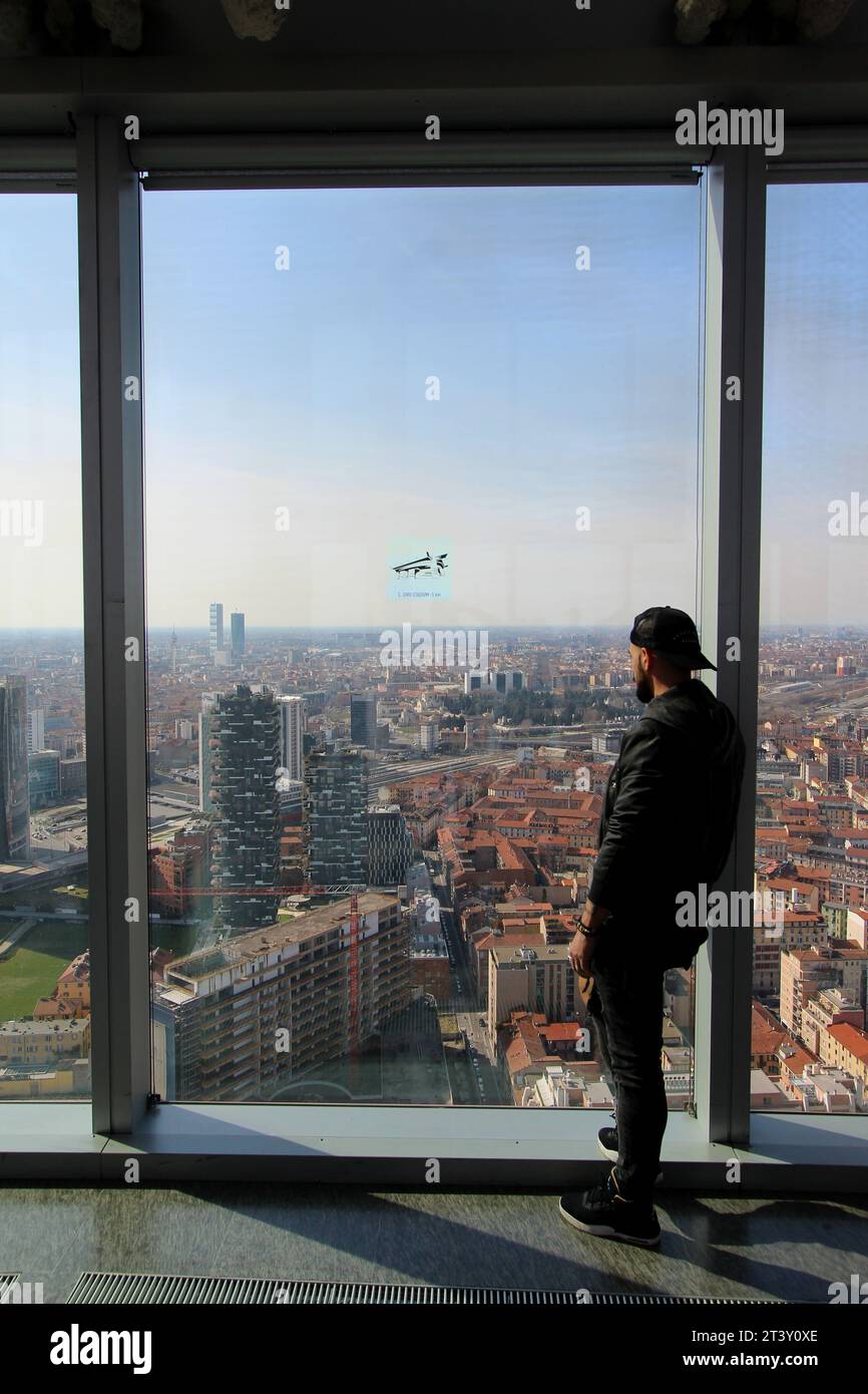 Milan, Italy. Man looks out of the windows in top floor of Palazzo Lombardia in a sunny spring day. Stock Photo