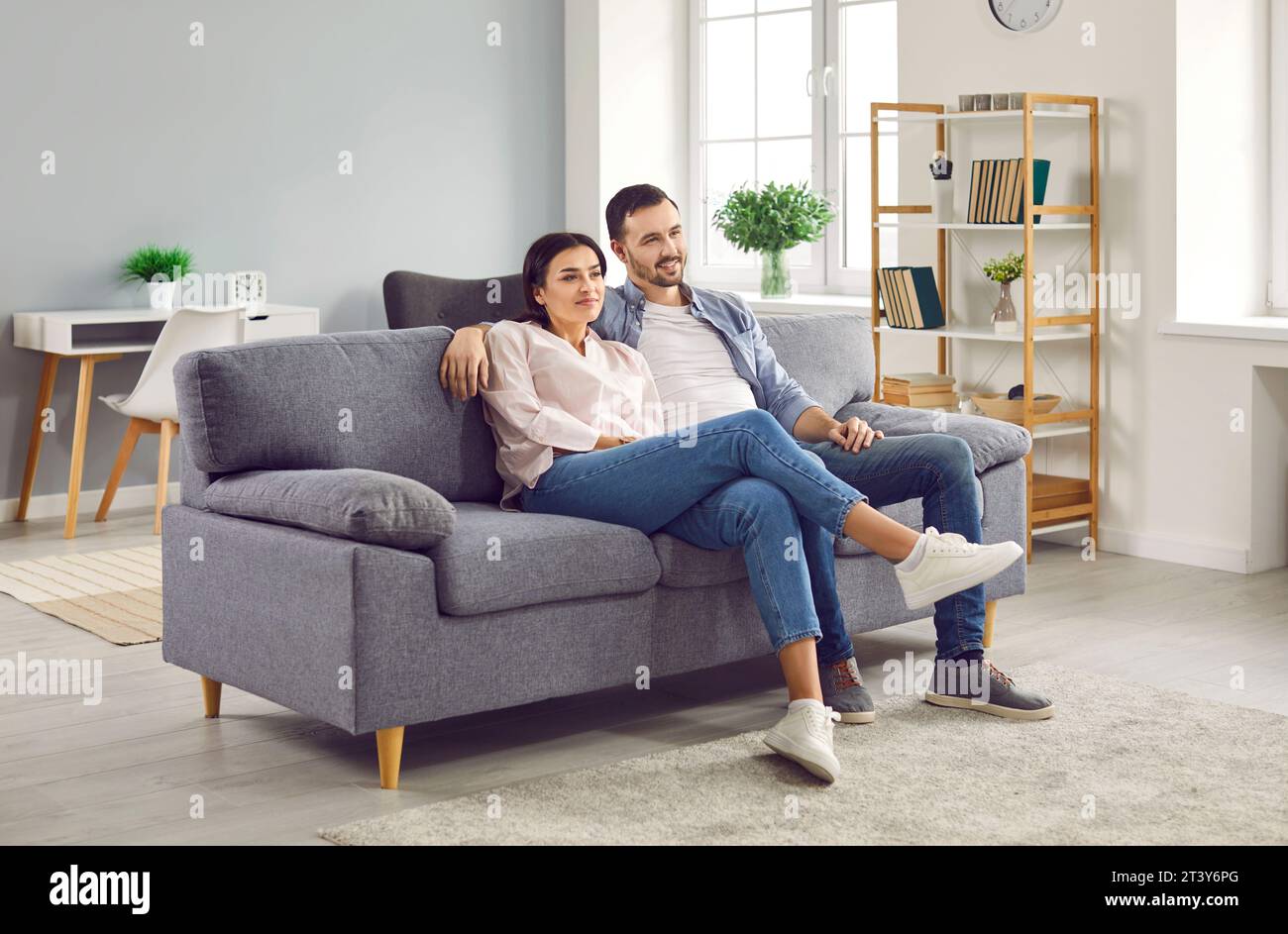 Happy relaxed young family couple sitting on sofa at home Stock Photo