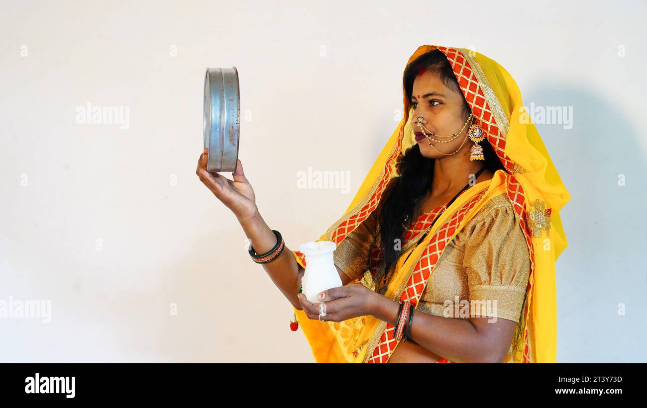 Young Rajasthani woman of Indian ethnicity looking through sieve on Karwa Chauth festival. Stock Photo