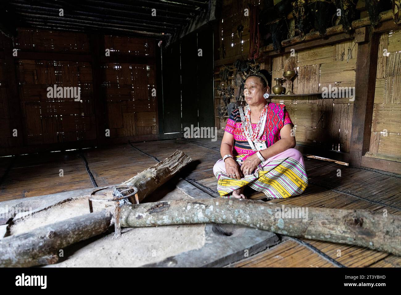 Woman from Adi tribe in traditional clothes sitting by the fireplace in traditional wooden house in Assam, Northeast India Stock Photo