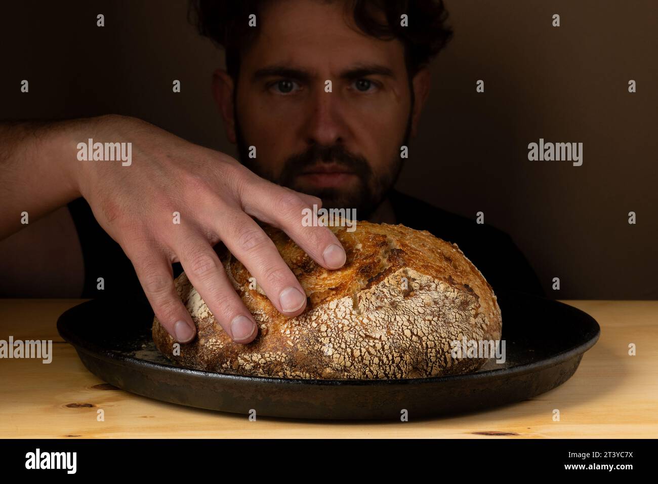 Attractive young Caucasian chef posing with white sourdough bread. The sourdough bread is the central protagonist of the scene, standing out with beau Stock Photo