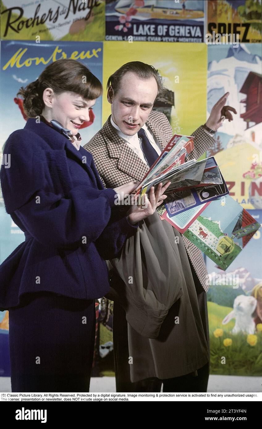 The actors and married couple Anita Björk and Olof Bergström. They are photographed in front of posters of European destinations such as Montraeux and Lake of Geneva. They read travel brochures and travel catalogs together. Perhaps to plan a holiday or to be curious about what the various destinations can offer. In the 1950s, European travel was something quite new, at that time they began to organize trips by bus to European cities and at the end of the 1950s the first charter trips by air premiered. Sweden in 1950 Stock Photo