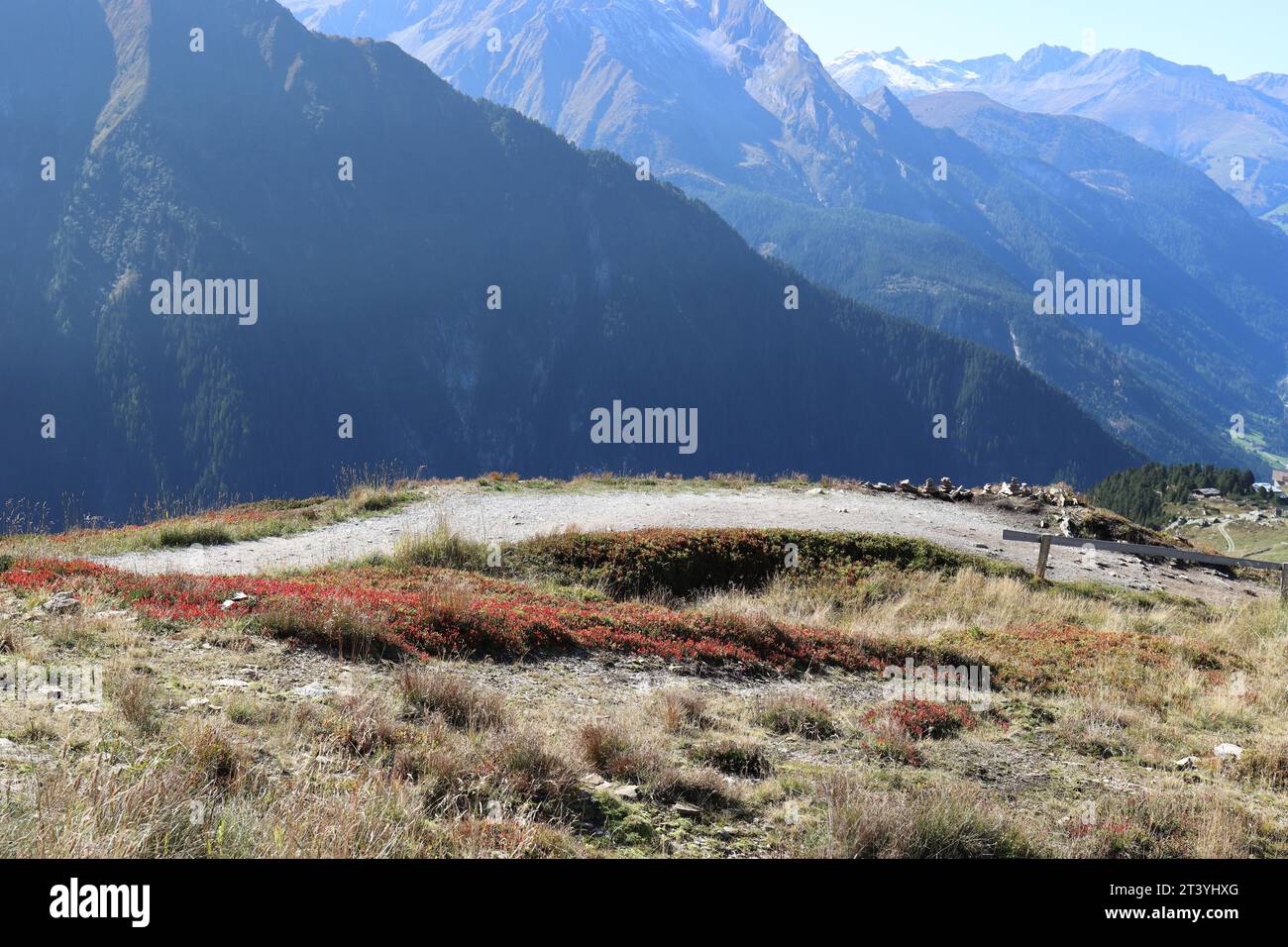 Wide-angle view of a sunlit hiking trail in the Austrian Alps against an impressive mountain backdrop Stock Photo