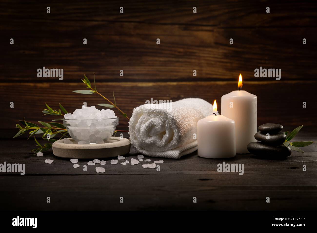 wellness spa. body skin care items on dark wooden table. towel, bath crystals, massage stones and candle Stock Photo
