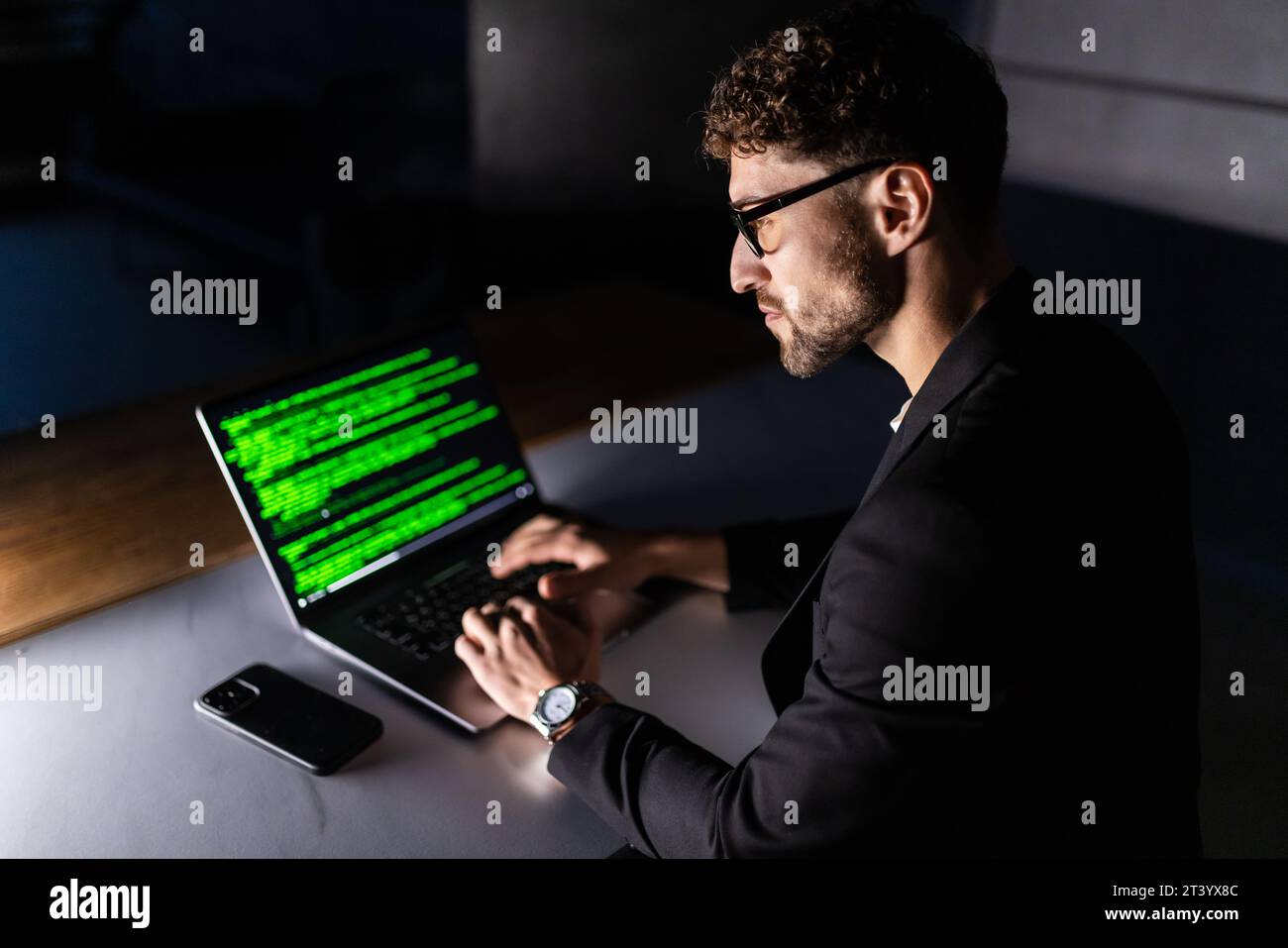 Young man mobile developer writes program code on a computer, programmer work in home office. Stock Photo