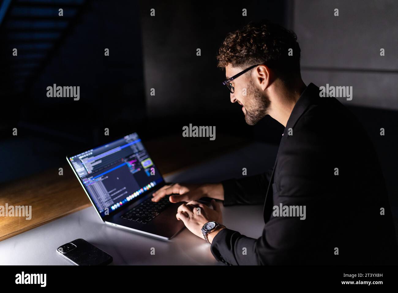 Young man mobile developer writes program code on a computer, programmer work in home office. Stock Photo