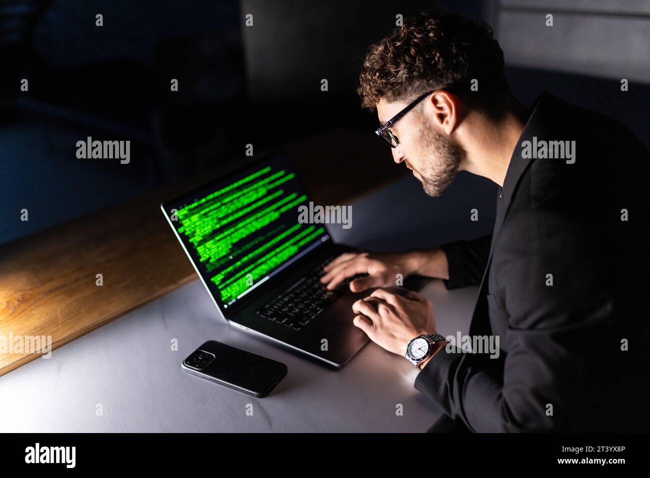 Young man mobile developer writes program code on a computer, programmer work in home office. Stock Photo