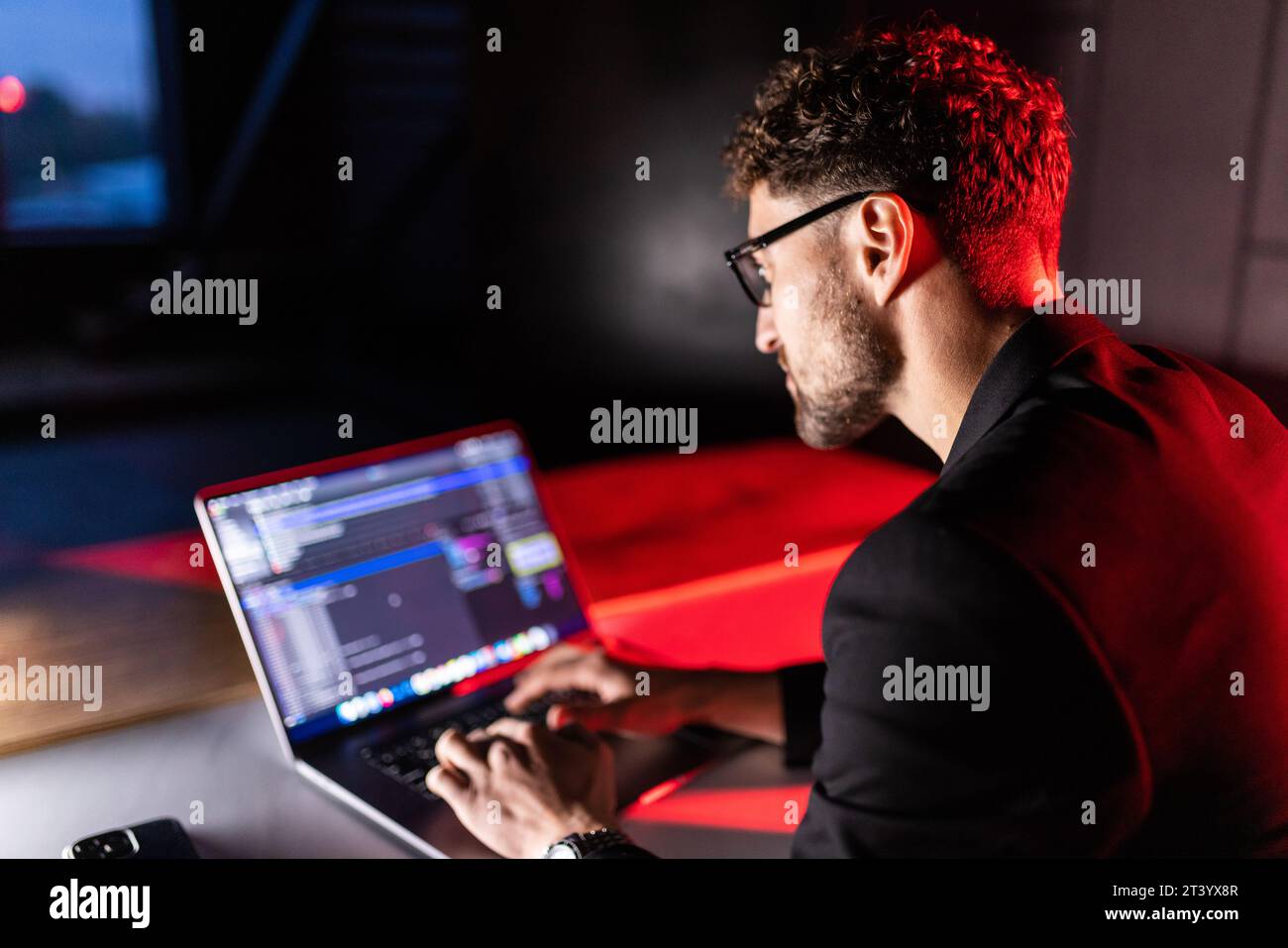 Young man mobile developer writes program code on a computer, programmer work in home office. Stock Photo