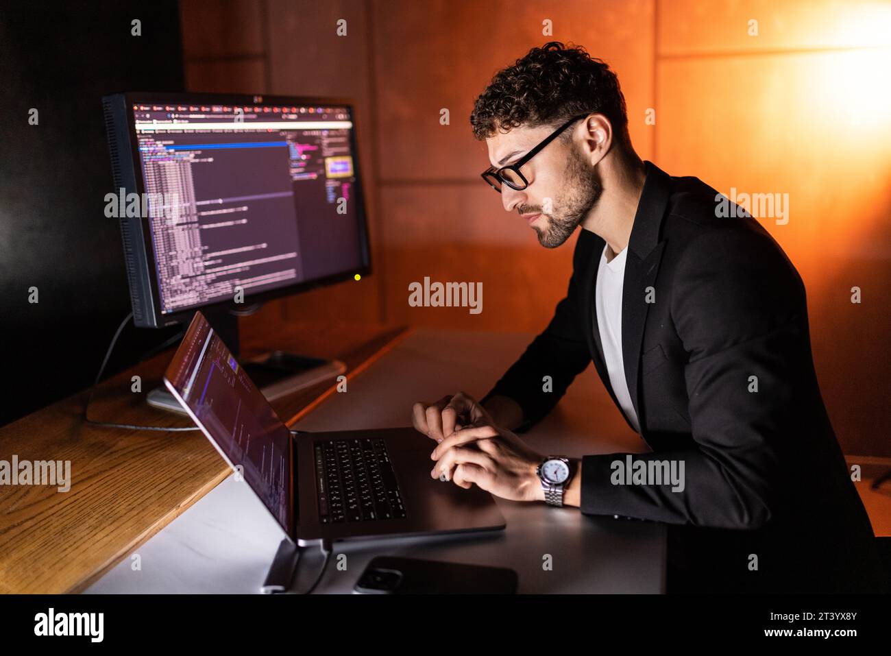Young man mobile developer writes program code on a computer, programmer work in home office. Stock Photo