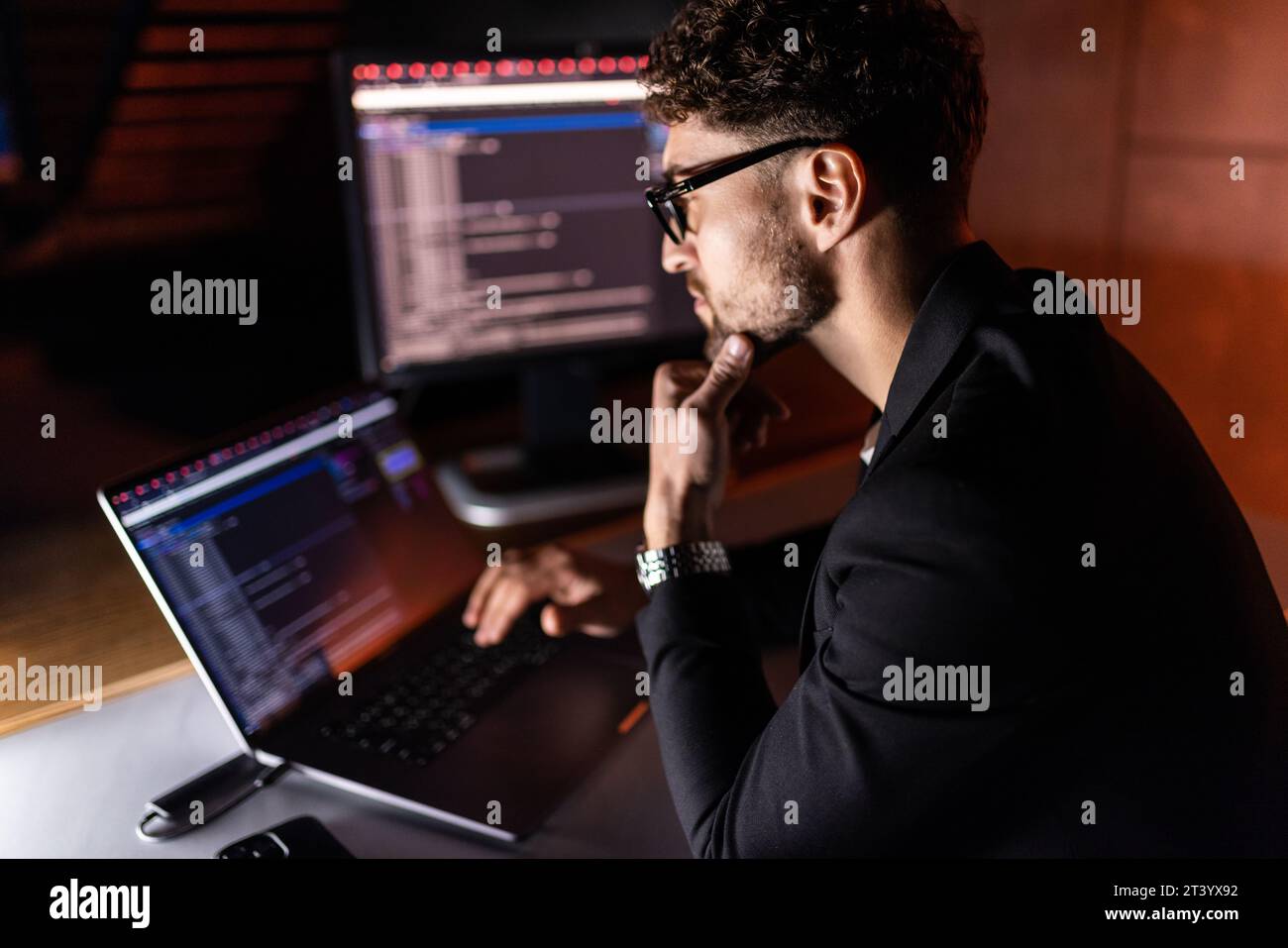 Young man mobile developer writes program code on a computer, programmer work in home office. Stock Photo