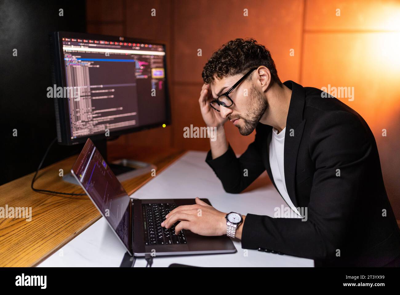 Young man mobile developer writes program code on a computer, programmer work in home office. Stock Photo