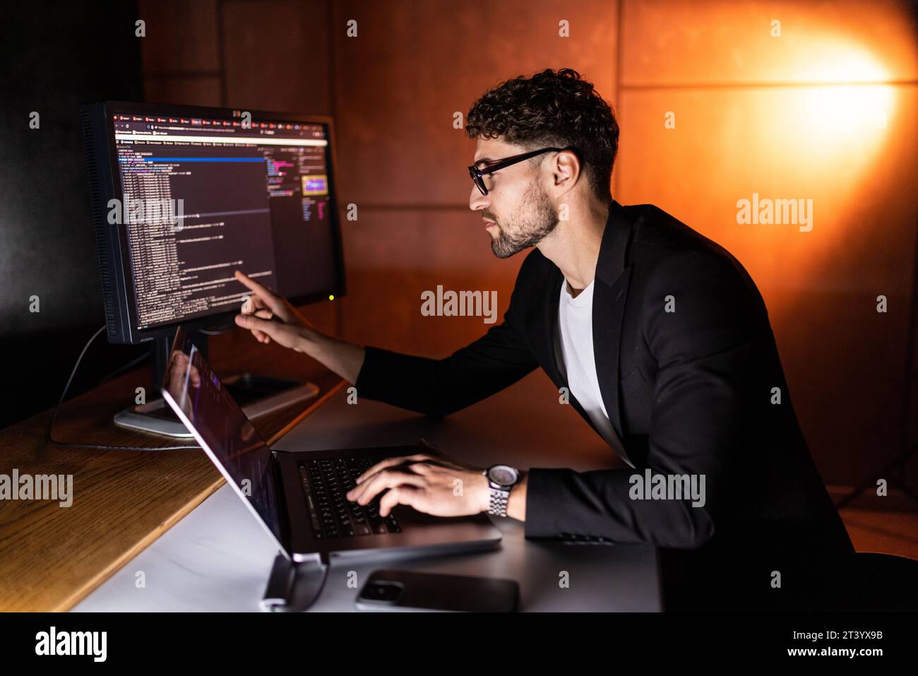 Young man mobile developer writes program code on a computer, programmer work in home office. Stock Photo