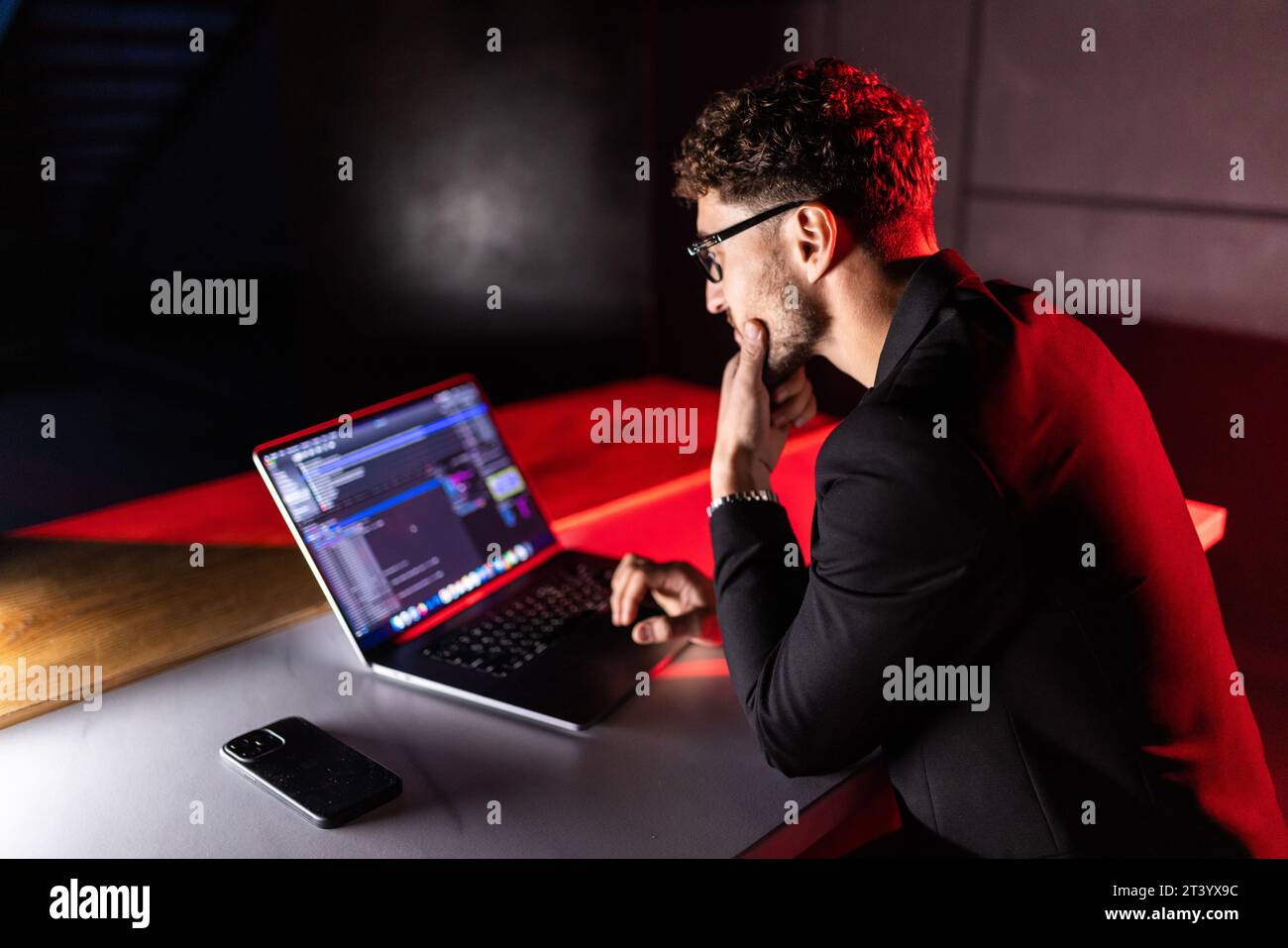 Young man mobile developer writes program code on a computer, programmer work in home office. Stock Photo