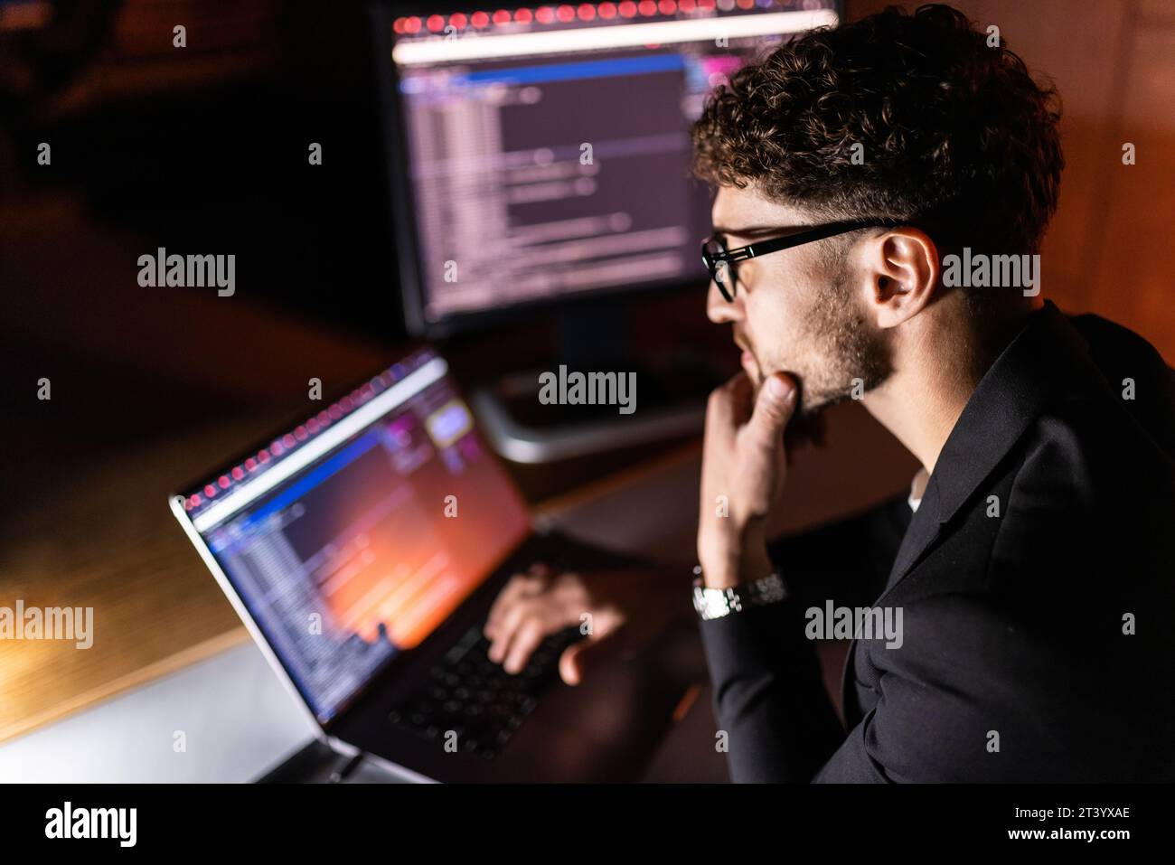 Young man mobile developer writes program code on a computer, programmer work in home office. Stock Photo