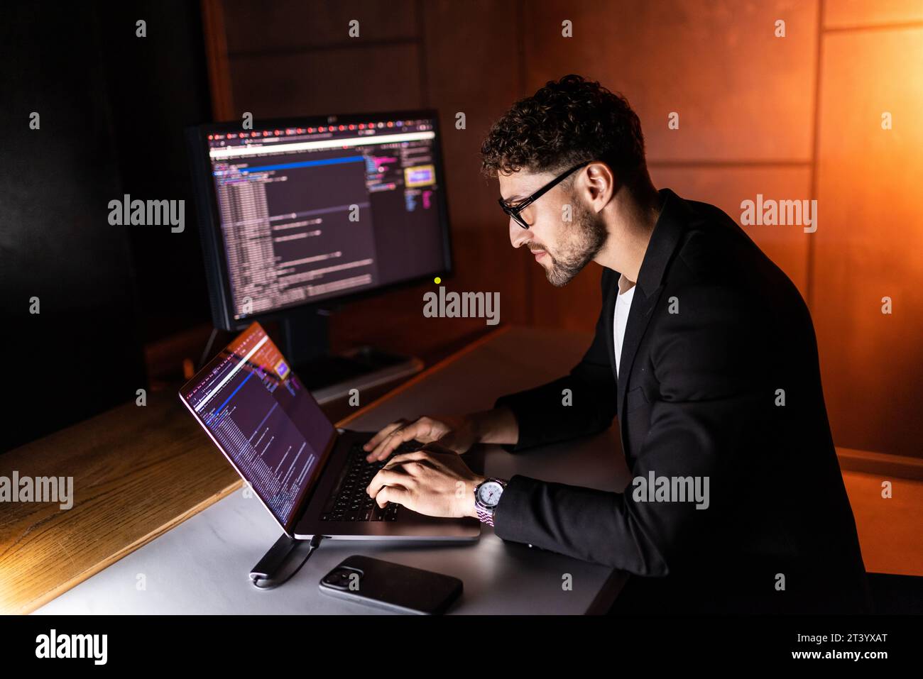 Young man mobile developer writes program code on a computer, programmer work in home office. Stock Photo