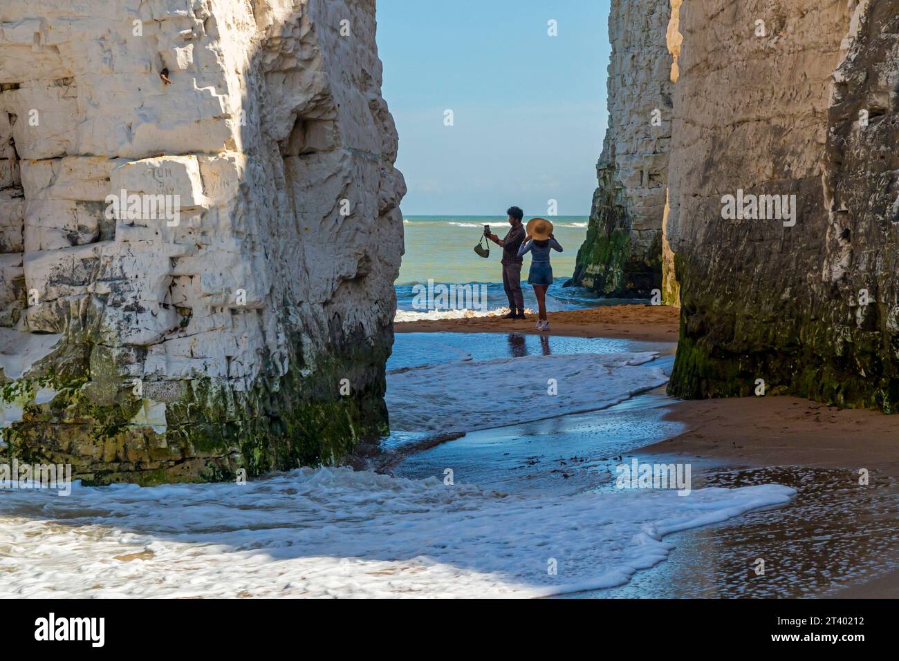Couple in sea next to chalk cliffs and stacks on the beach at Botany Bay near Broadstairs on the north east coast of Kent in southern England UK. Stock Photo