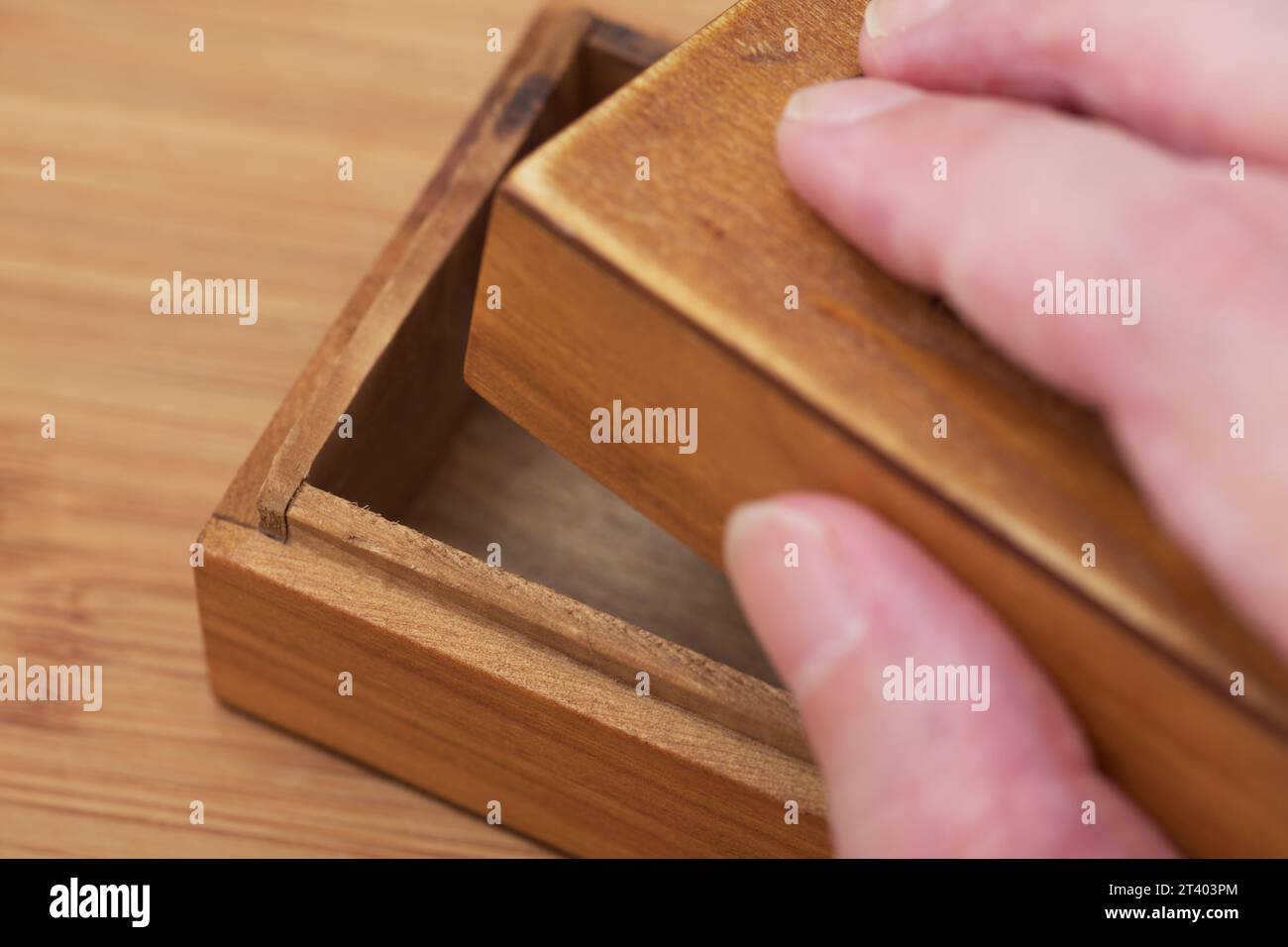A man opening a small old empty wooden box with his hand. Close-up. Stock Photo