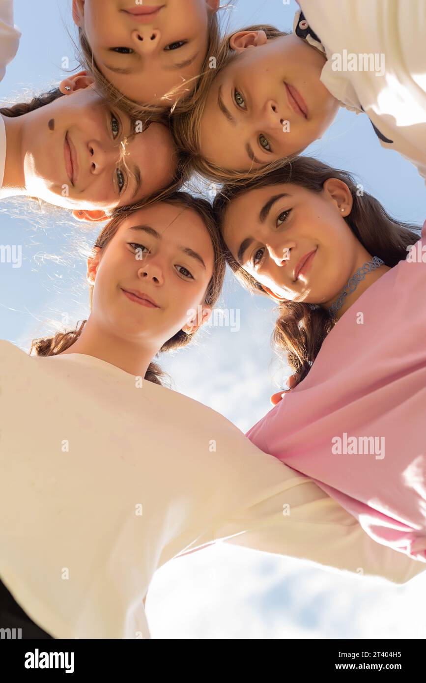 Five friends huddled in a circle, looking at the camera and smiling. Friendship and unity among girls. Friends forever. Adolescence and puberty Stock Photo
