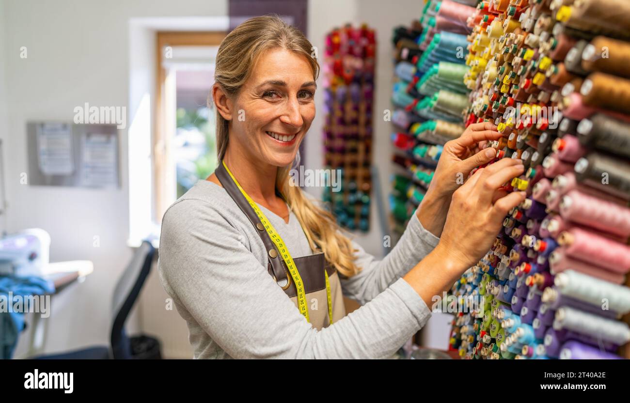 cheerful seamstress woman with a measuring tape around her neck is ...