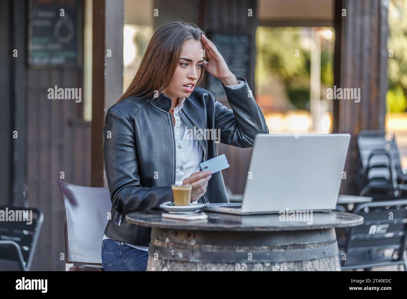 Young frustrated female bookmaker sitting in street cafe touching head ...