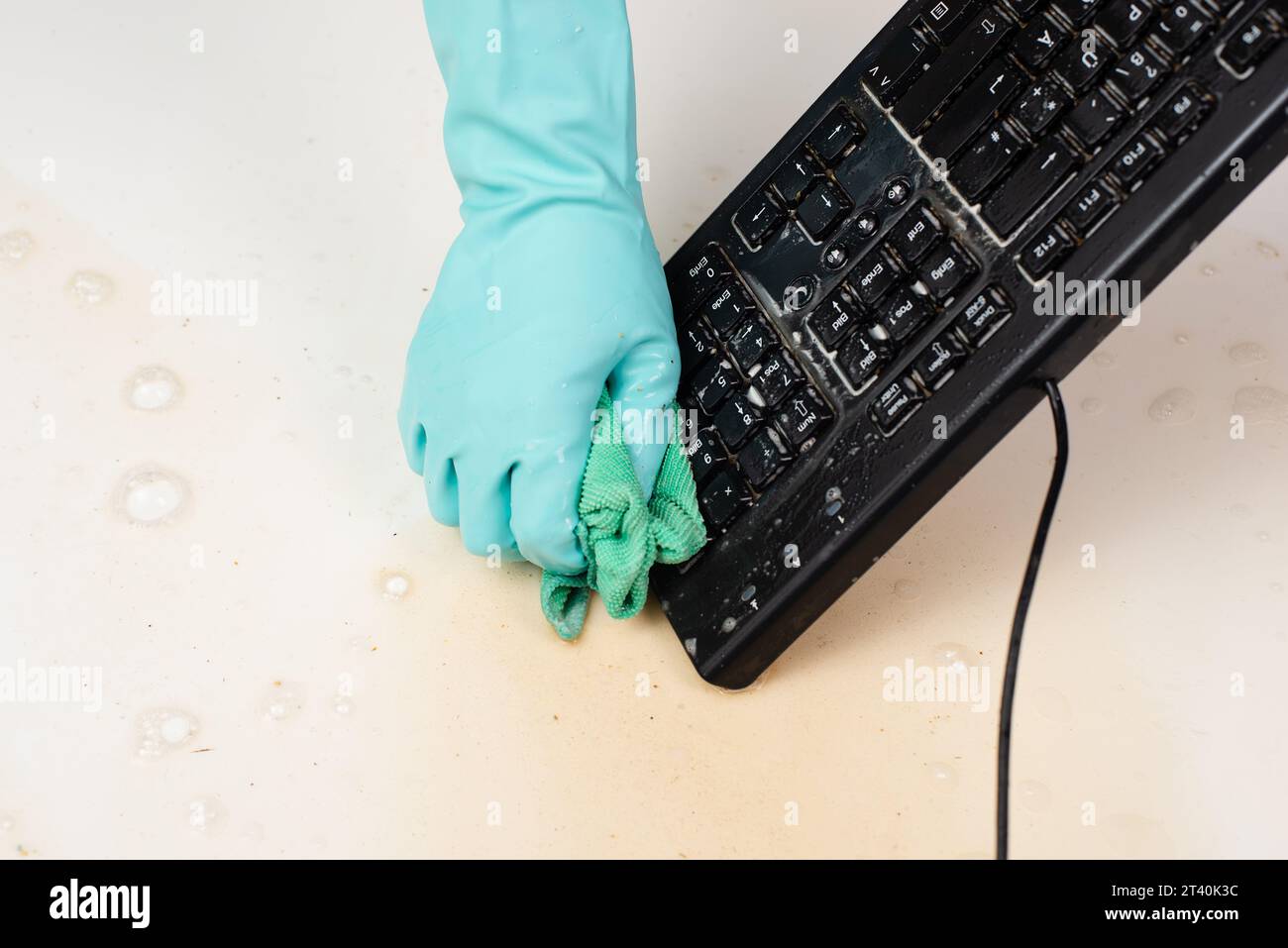 Cleaning computer keyboard in office with rubber protective glove ...