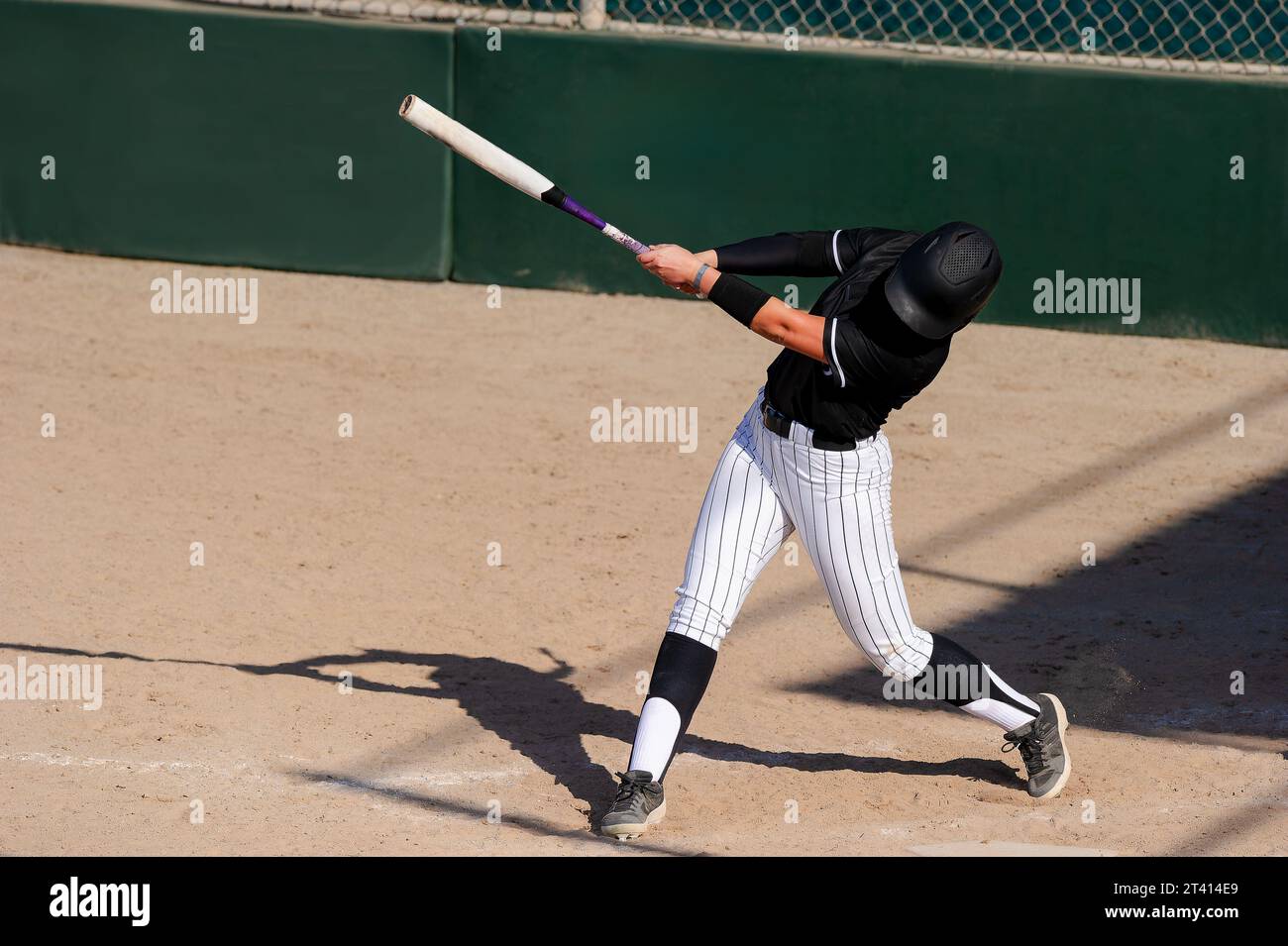 A Baseball Softball Player Is Swinging The Bat Hitting The Ball Stock