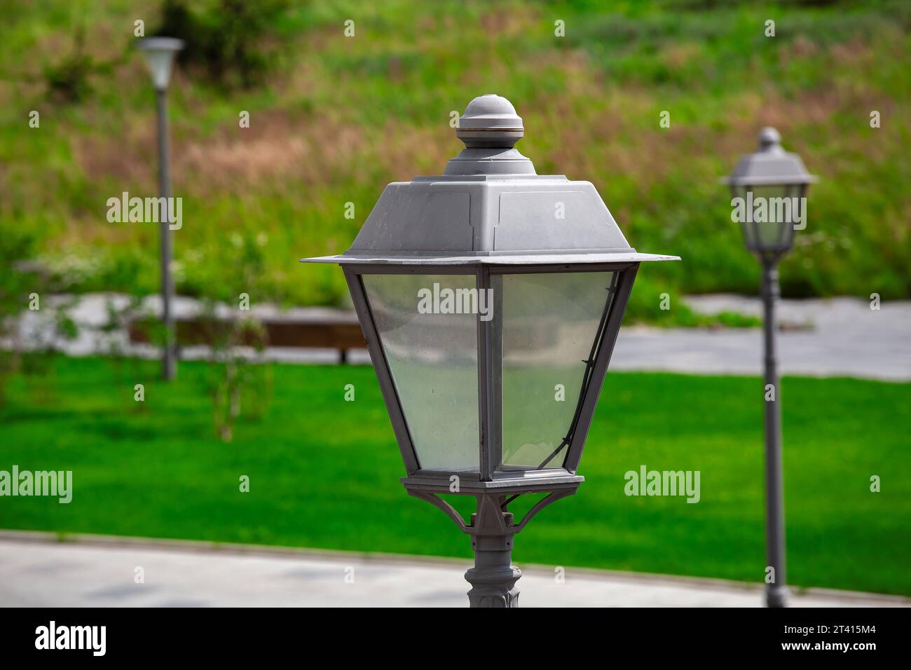 iron lantern in a park with green plants on a summer sunny day, close-up of the lighting fixture. Stock Photo