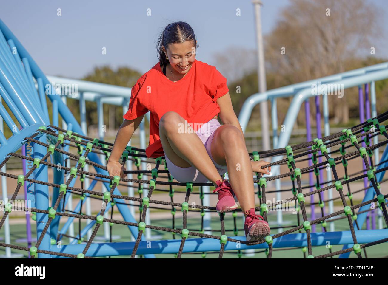 Latin girl climbing a net in a public park. Stock Photo