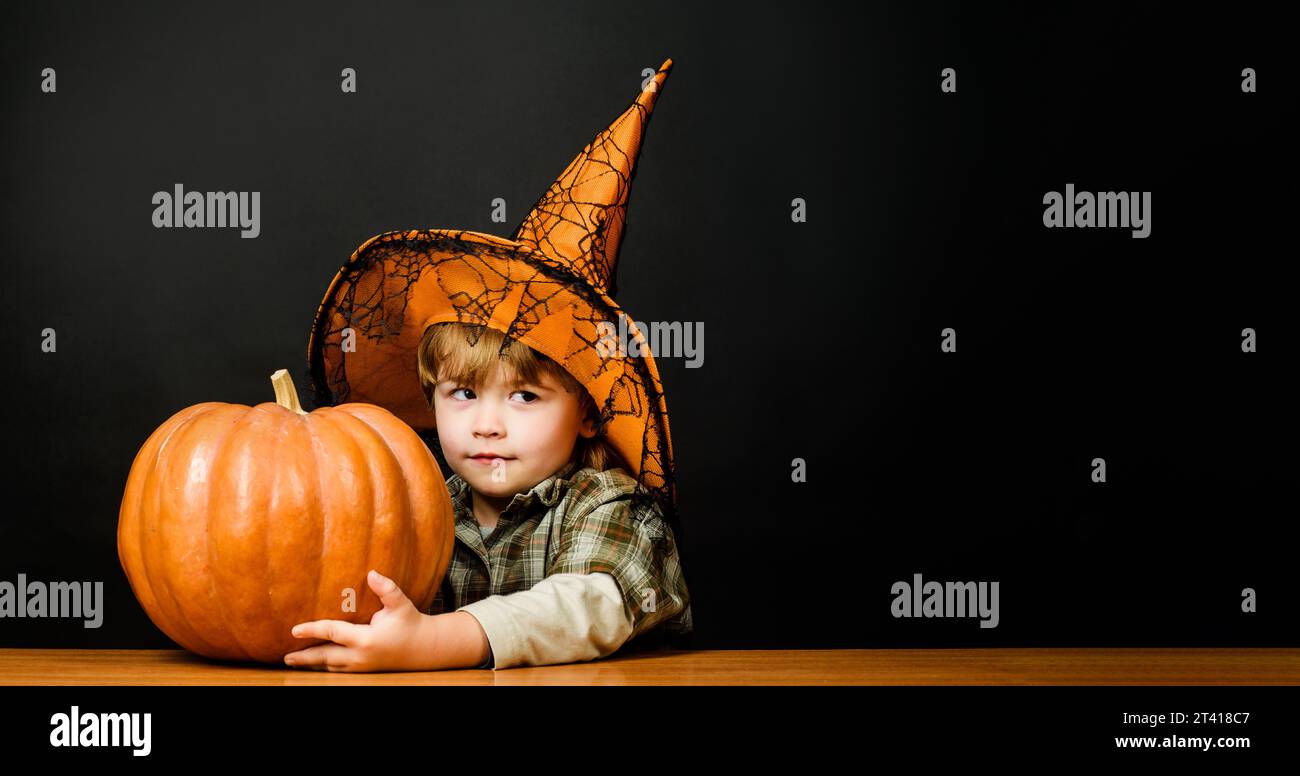 Cute kid boy in witch hat with Halloween pumpkin. Preparation for Halloween holidays. Thanksgiving day cooking. Halloween child with jack-o-lantern Stock Photo